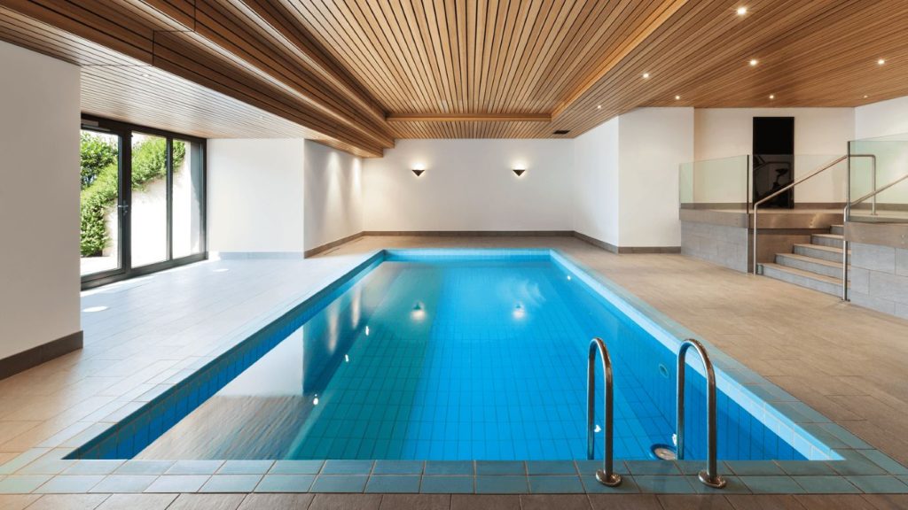 luxurious indoor swimming pool featuring a sleek wooden slat ceiling, large glass doors, and contemporary design elements